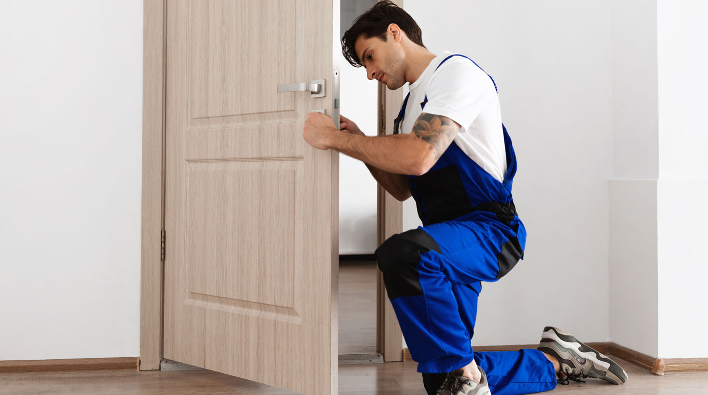 Installateur professionnel ajustant une porte d'entrée avec un niveau à bulle dans un chantier propre.